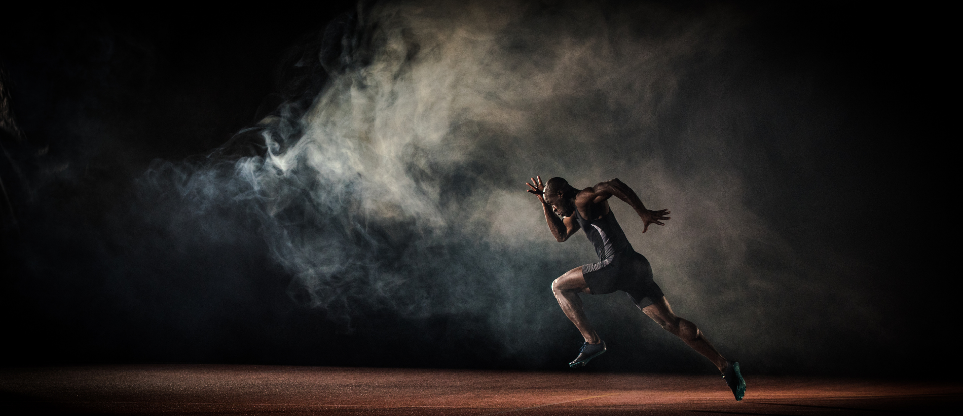 Young male athlete running on race track.