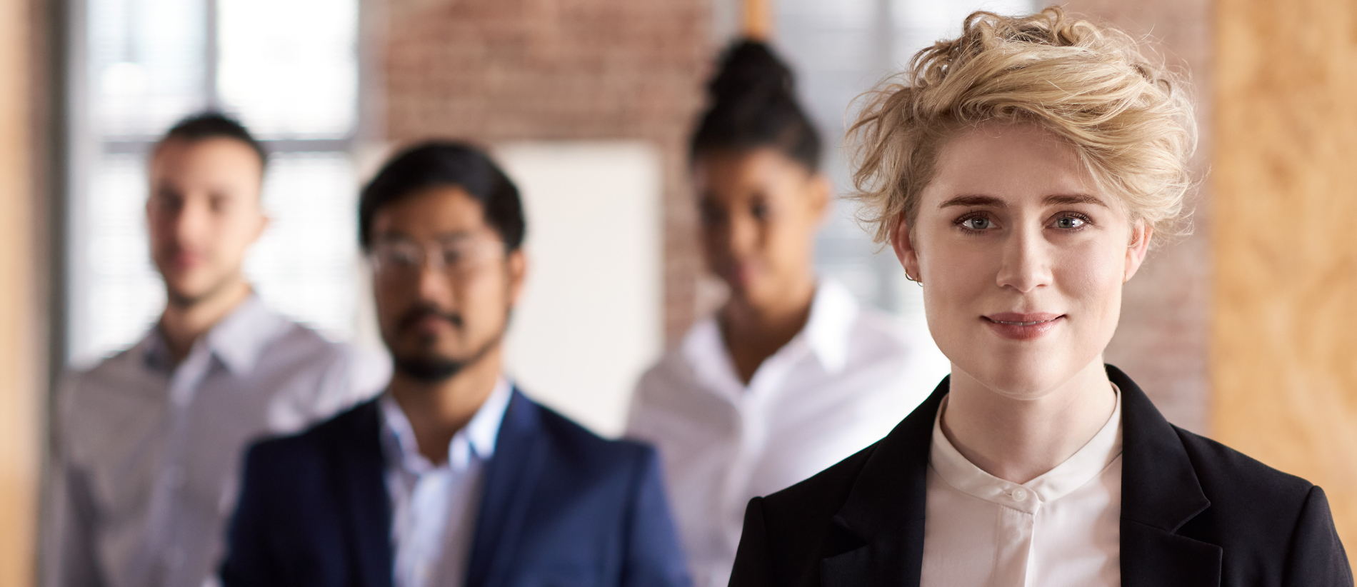 Business woman looking straight at camera, colleagues soft focus in the background