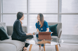 Asian chinese female doctor explaining medical report To a female Patient at her office sofa