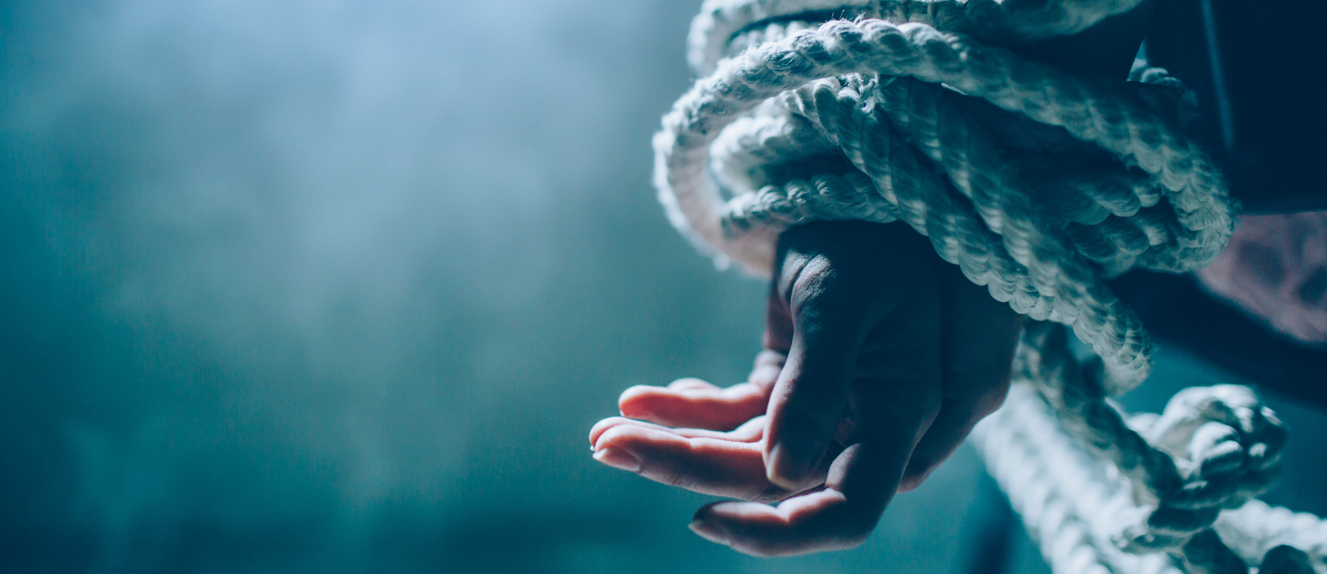 Close up and cut view of woman's hands tied in a knot with a rope behind her back
