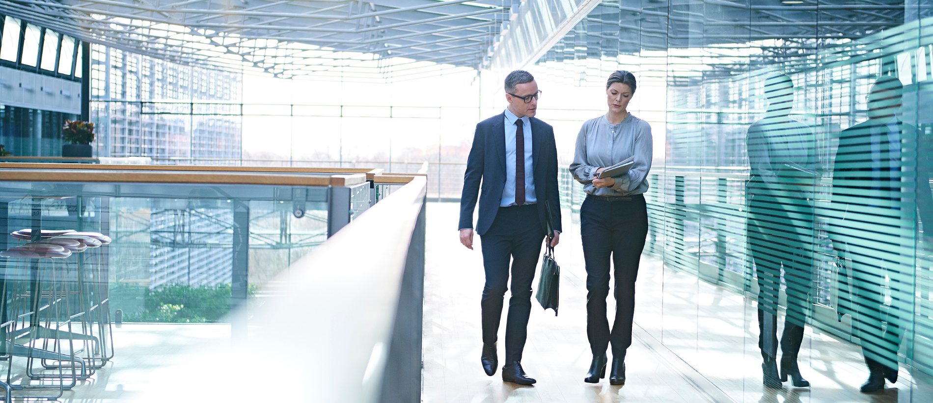 Businessman and woman walking and talking on office balcony