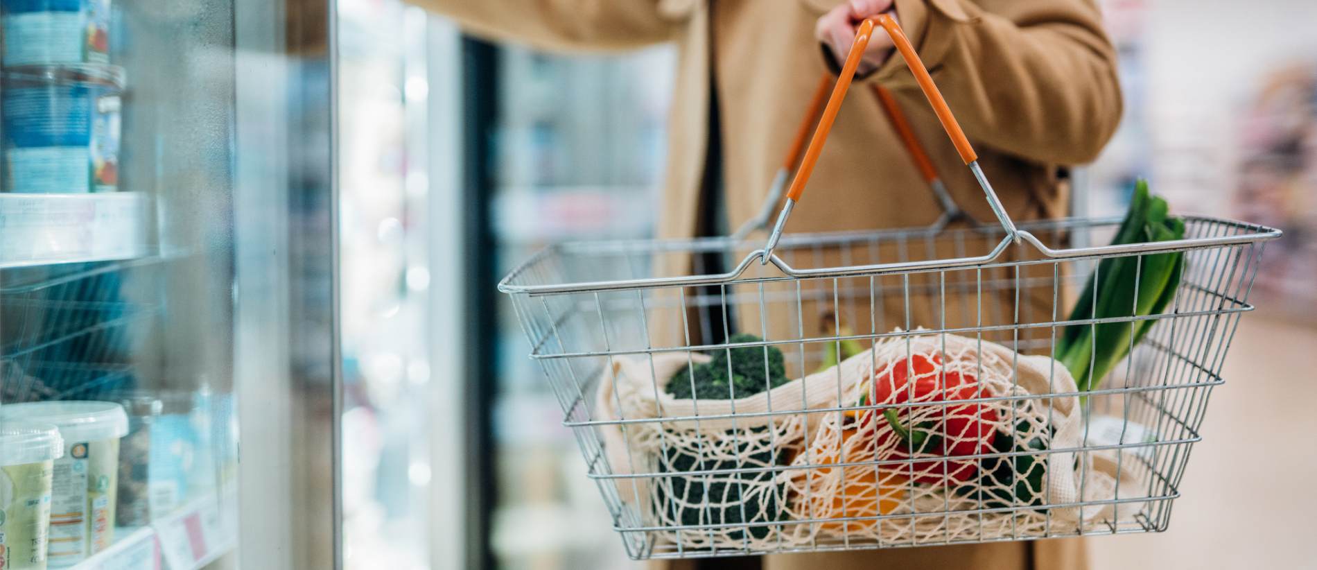 Cropped shot of woman carrying shopping basket and shopping groceries in supermarket