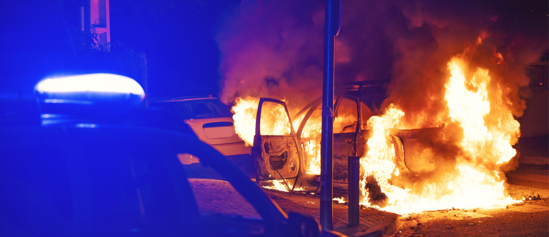 Police action during emergency with car in flames at night, riot, political violence