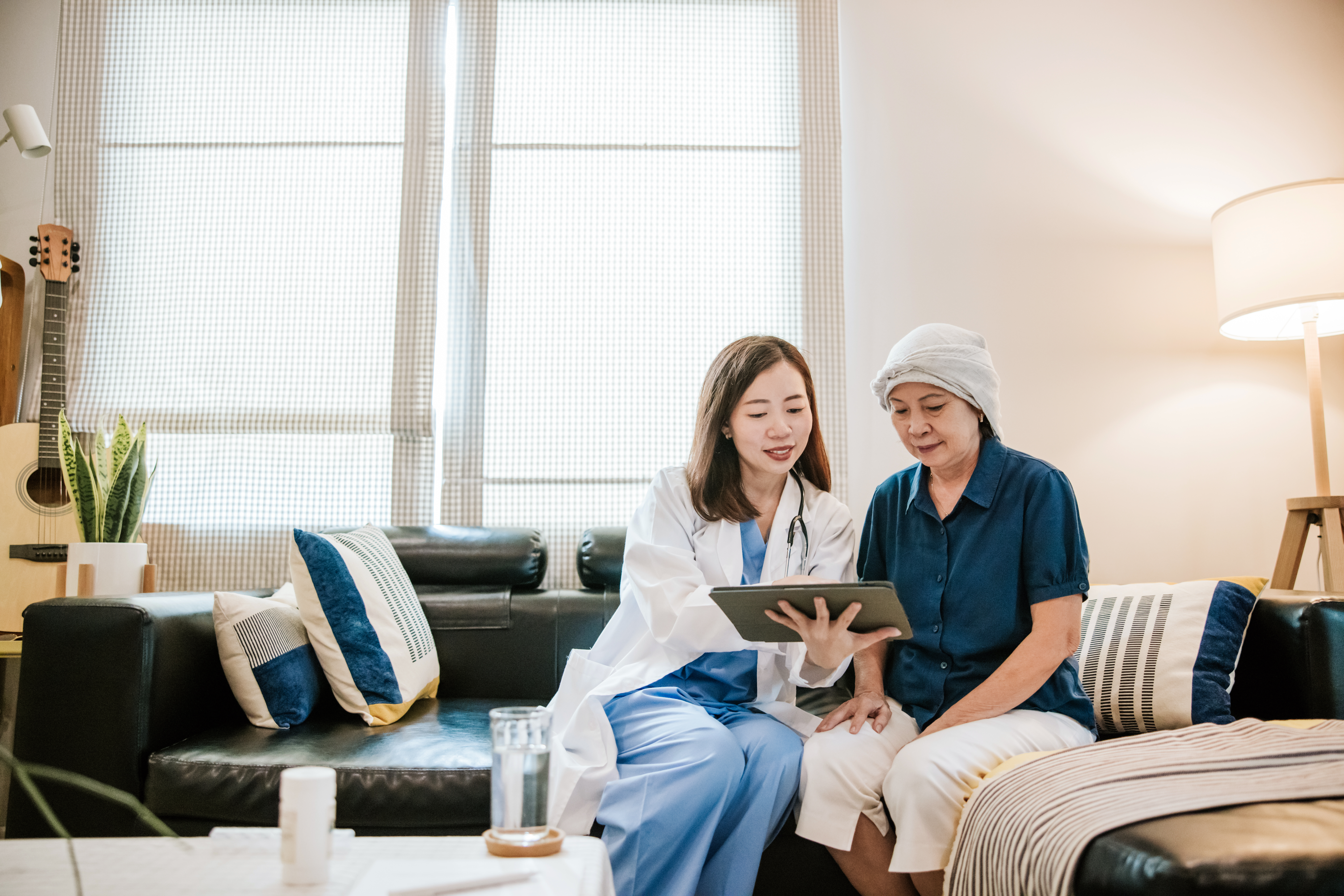 Young female doctor use tablet to explain her senior patient about cancer and medication for next step