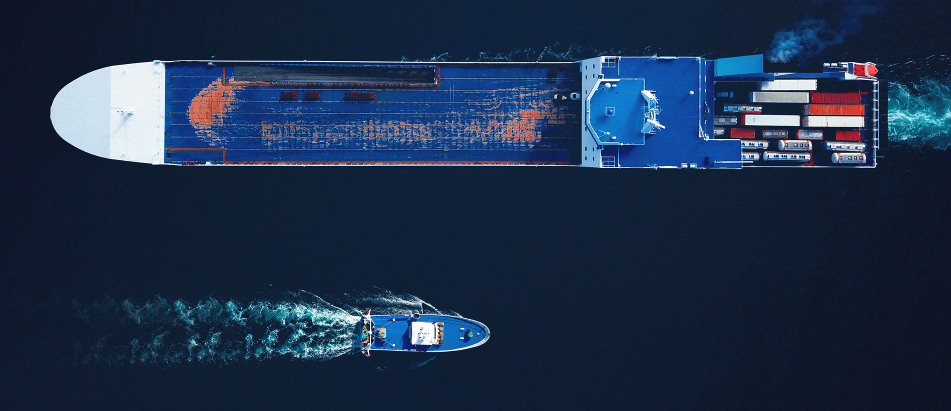 Aerial top view of a busy harbour. Large commercial ships cruising in the port