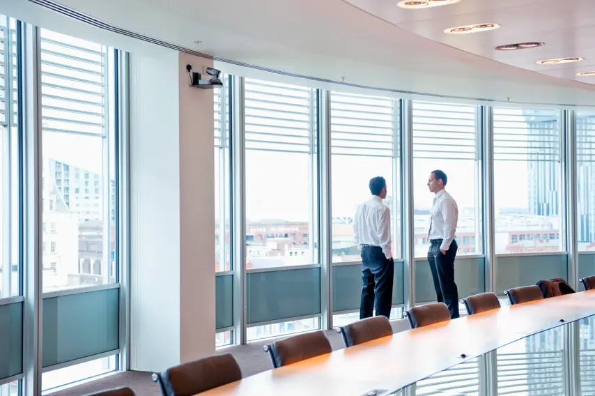 Businessmen talking near window in office conference room