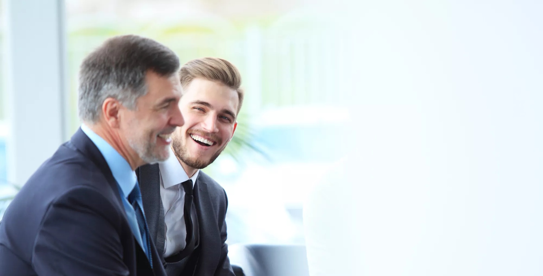 Mature businessman using a digital tablet to discuss information with a younger colleague in a modern business lounge