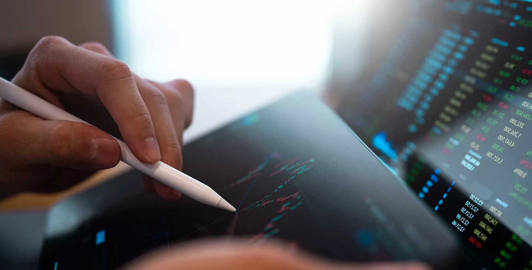 A business person tracking the technical movement of a stock chart on a computer screen.