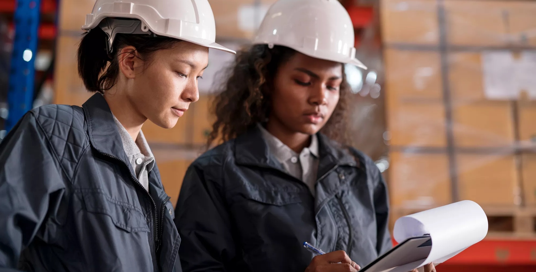 Inventory Lot Tracking to Eliminate Human Error in Warehouse Operations. A Female Warehouse Supervisor has a discussion with warehouse staff over a lot control checklist to verify in case of a product recall in a distribution warehouse.