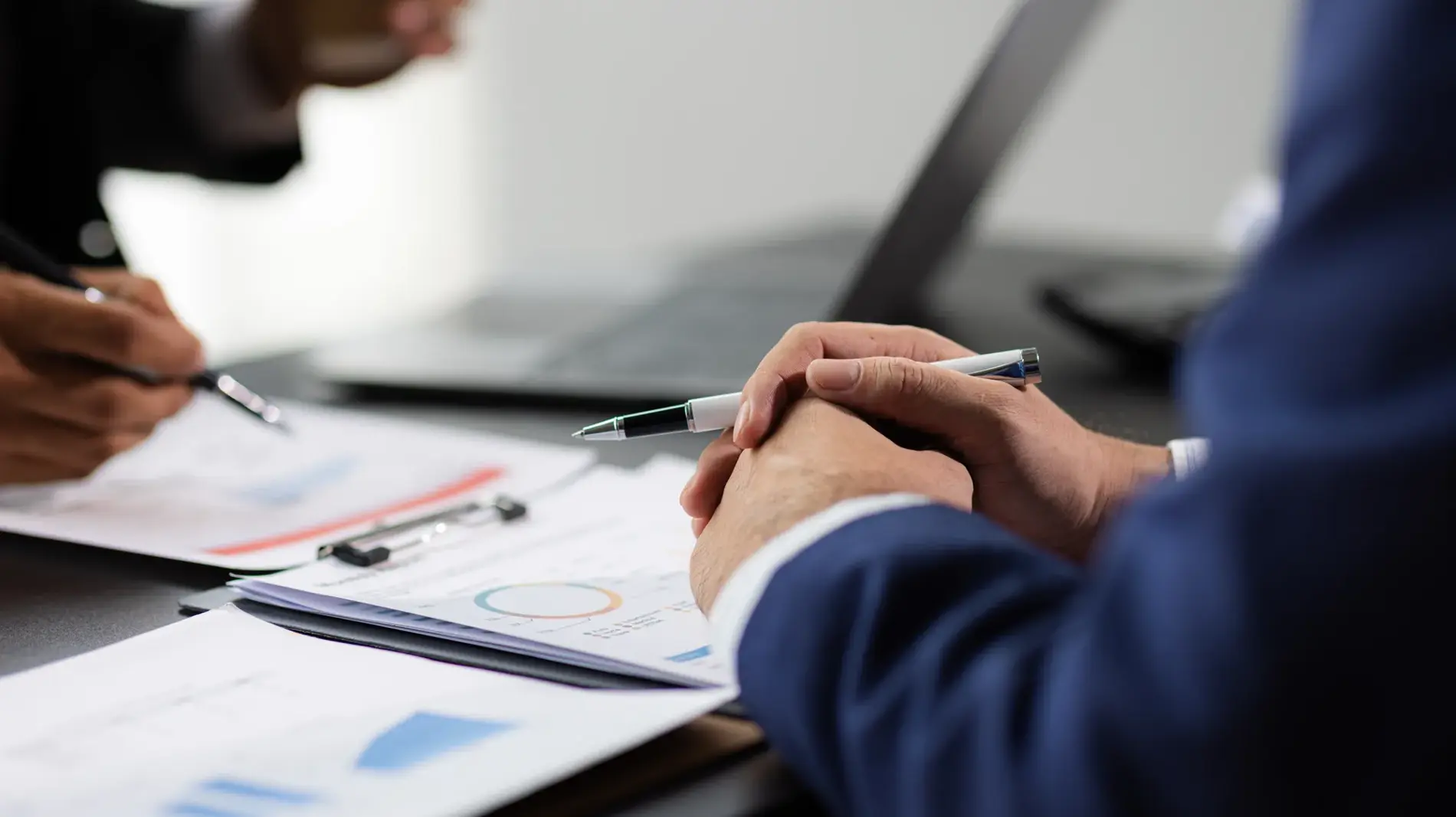 Businessman and financial advisor analyzing financial charts and graphs on document during meeting. Businesspeople are discussing financial data and pointing at charts and graphs on financial reports.