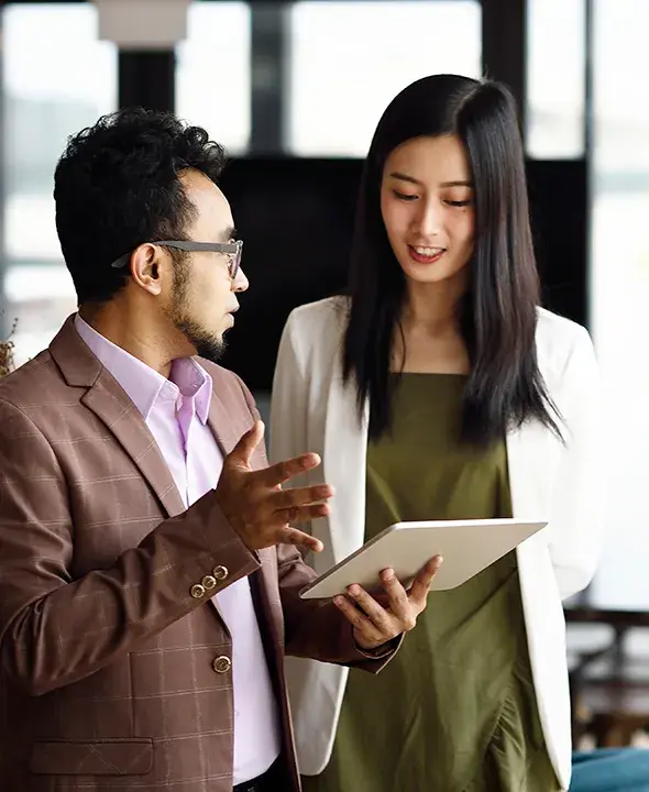 Two Asian business people discussing and holding a tablet.