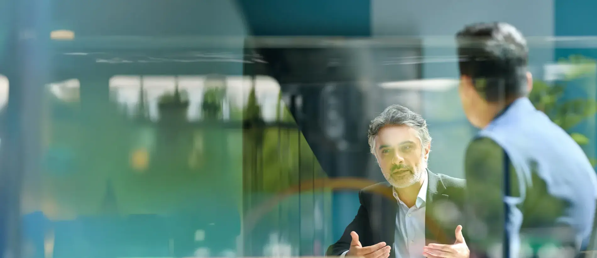 Mature businessman sitting on office balcony having meeting with colleague discussing project and gesturing, planning, togetherness, discussion