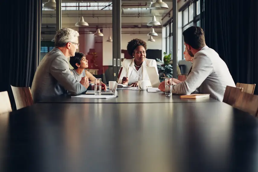 African American businesswoman discussing work with her diverse team during a meeting together in an office boardroom