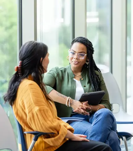 An unrecognizable young adult woman shares her problems with the young adult female counselor.