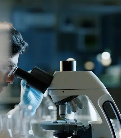 Doctor, microscope and analysis in lab for medical study, scientific innovation and stem cell research. Indian man, investigation and experiment with biotechnology for dna, exam or test for bacteria