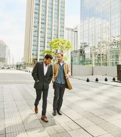 Wide shot of businessmen having in discussion while walking in front of buildings in downtown financial district