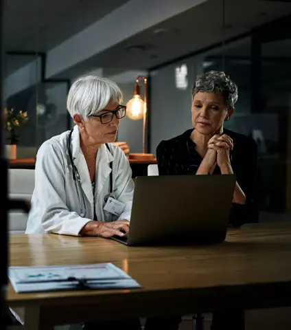 Shot of two experienced female medical professionals working on a laptop together inside their office at a hospital at night