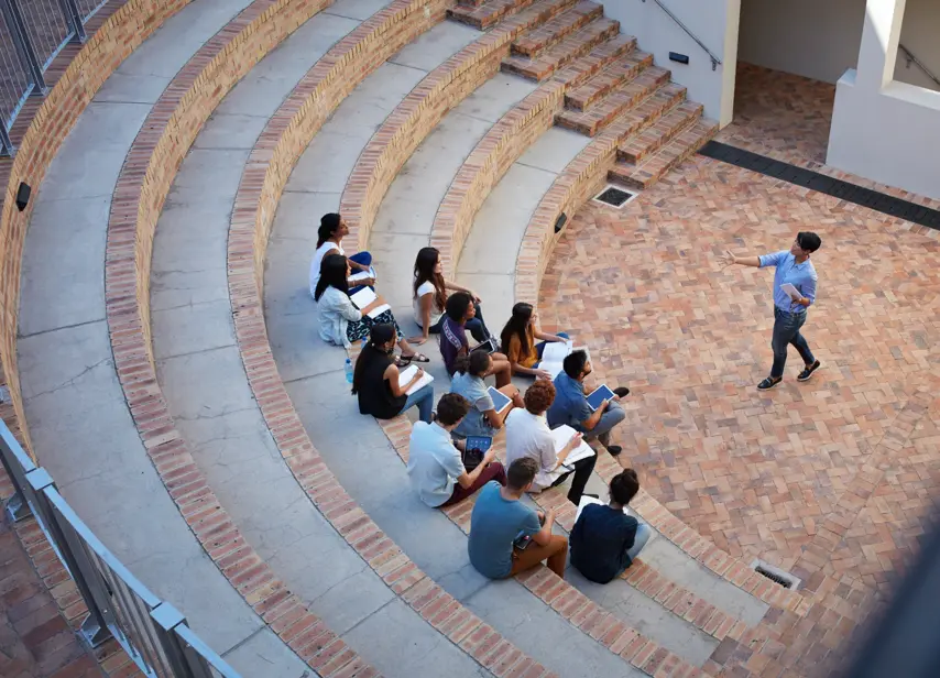 Students having class in outside auditorium, with tablets and books