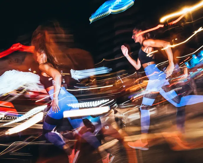 Two woman running in the city at night