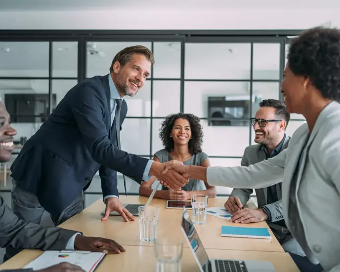 Entrepreneurs handshaking during a meeting with their colleagues in the office. Business persons shaking hands on a meeting.