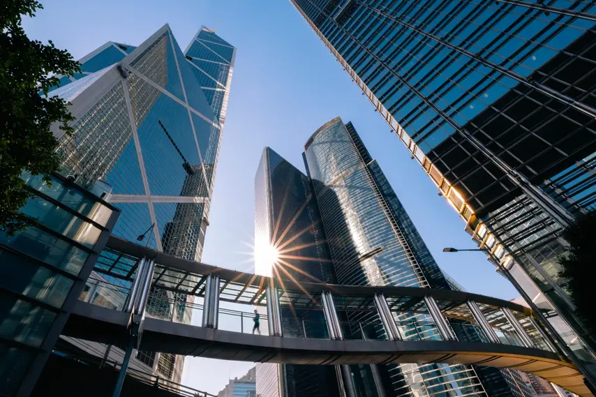 Person in blurred motion on footbridge connecting modern office buildings. Sunny morning in Central district in Hong Kong.