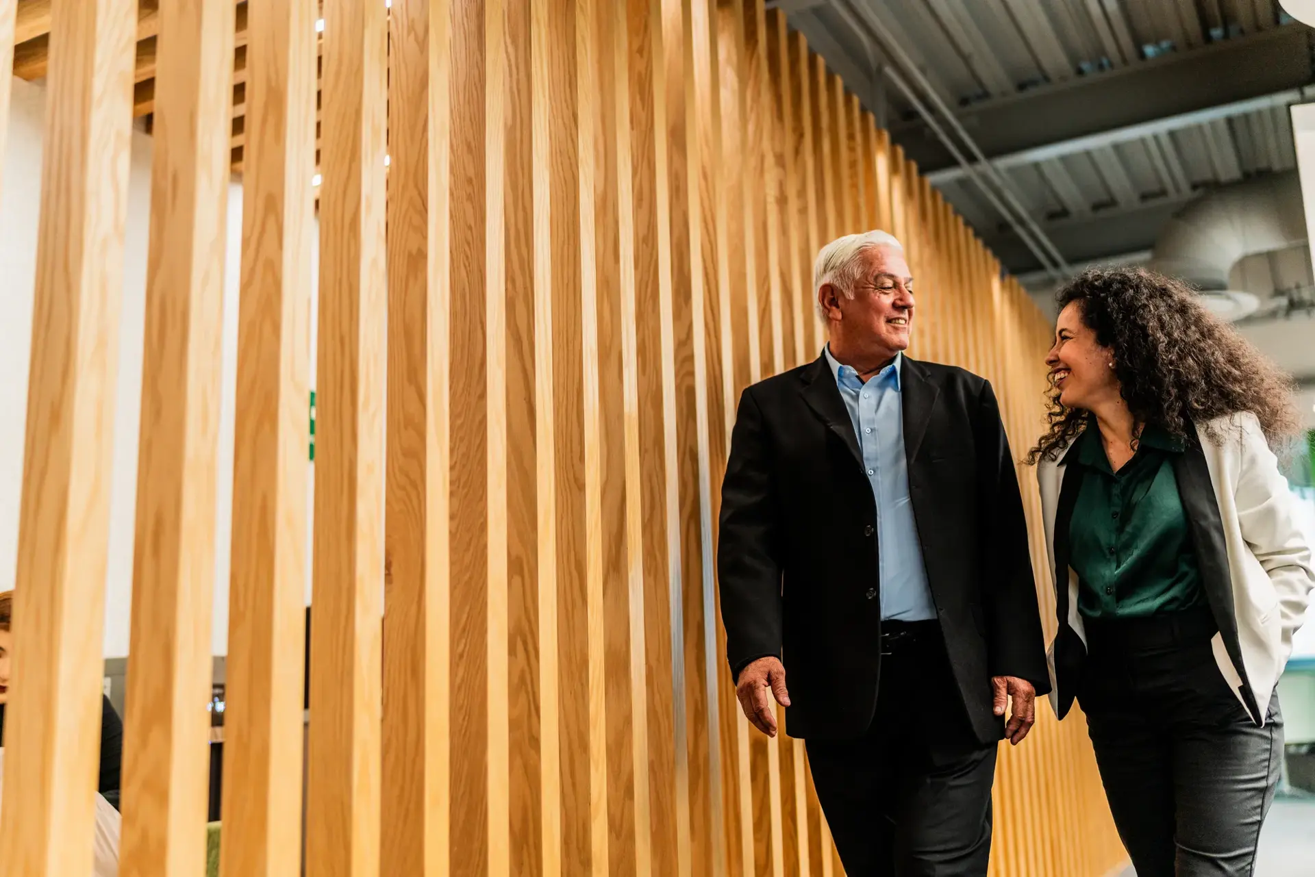Senior businessman walking and talking with employee at office