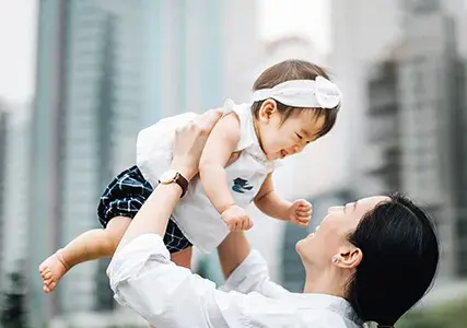 Asian woman holding baby in the air. Parenting stock photo.