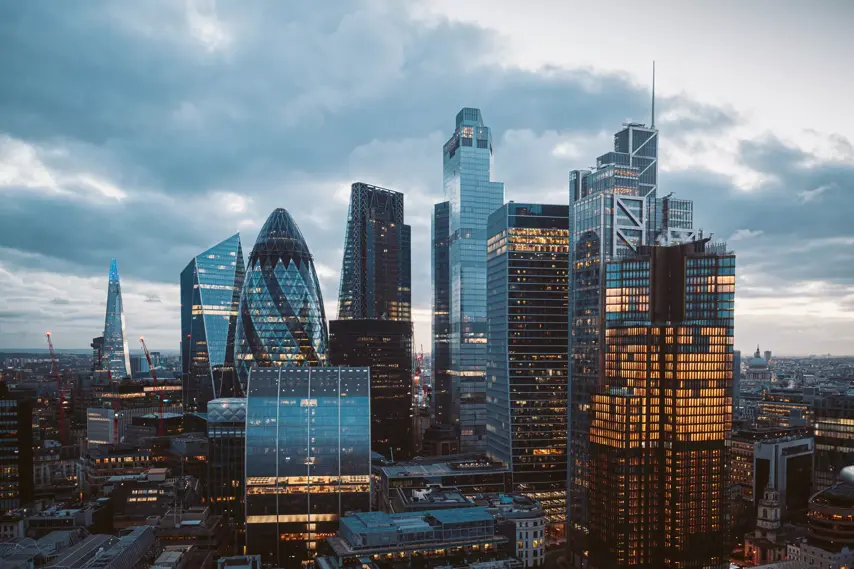 Aerial panoramic view of The City of London cityscape skyline with metropole financial district modern skyscrapers after sunset on night with illuminated buildings and cloudy sky in London, UK
