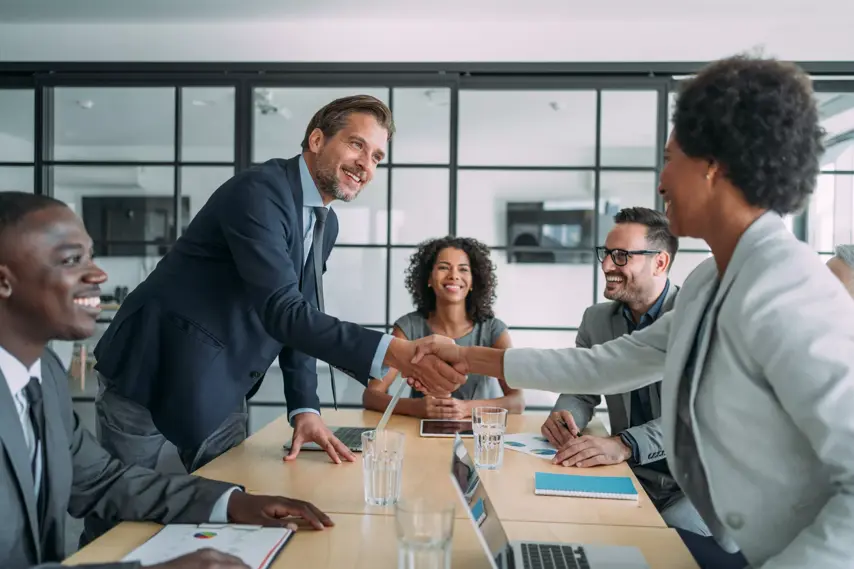 Entrepreneurs handshaking during a meeting with their colleagues in the office. Business persons shaking hands on a meeting.