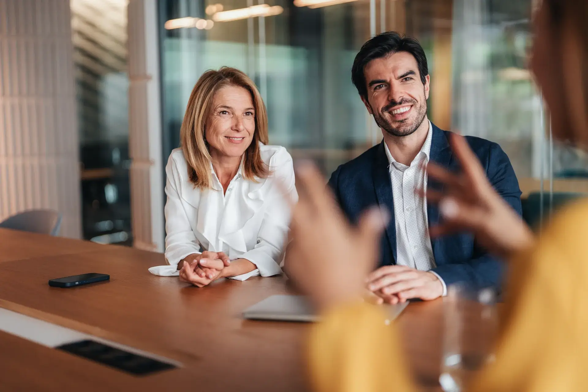 Focus on confident businesswoman and business woman, senior managers talking to client. Three entrepreneurs on meeting in board room discussing new agreement. Candidate talking to human resource team during a job interview in the office.  Company owner on a meeting with employee. Middle aged businesswoman in a conversation with a colleague. Lawyer or financial advisor consulting clients during formal meeting. Job interview and hiring process.
