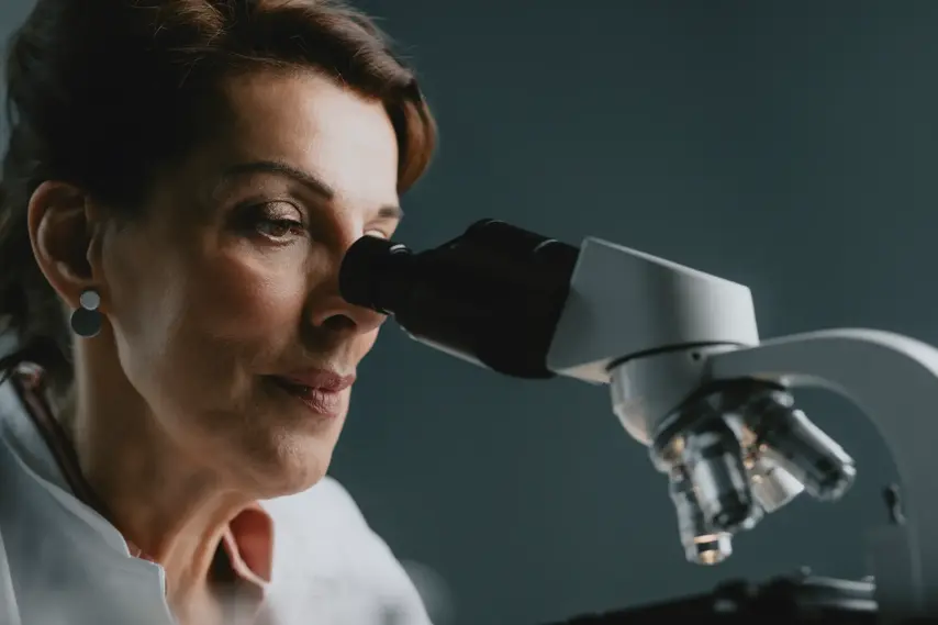 Night shift: a female researcher using a microscope at a lab at night.