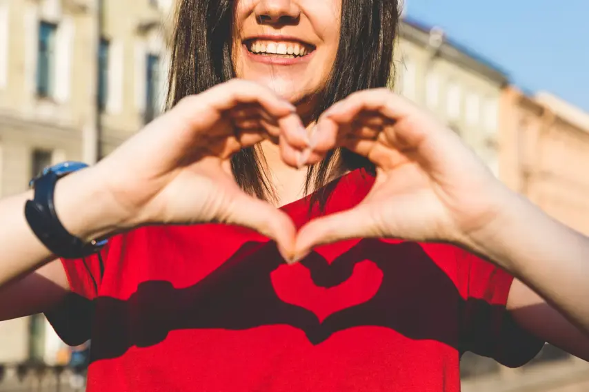 Russia, St Petersburg, heart shape with hands on red shirt by smiling girl