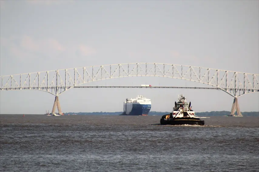 July 28, 2018, Baltimore, MD, USA. A small tug boat on the way in the Baltimore harbor to meet a large auto cargo ship under the Key Bridge.