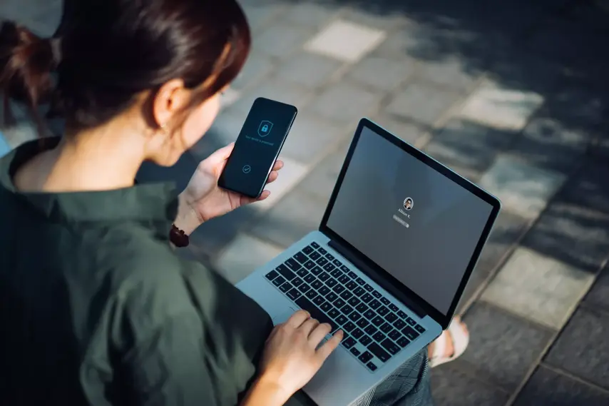 stock photo - Asian woman using mobile and laptop, showing login screen. Cyber security related.